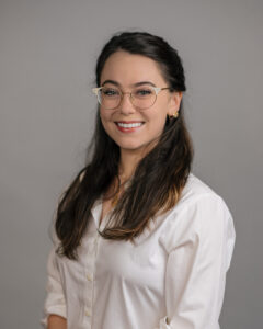 Ruby smiles for her headshot. She is wearing glasses and a white blouse. 